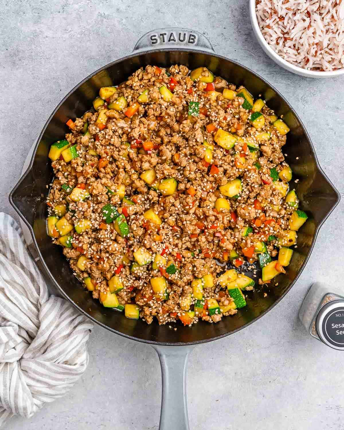 Ground turkey and vegetables in a skillet on a gray background.