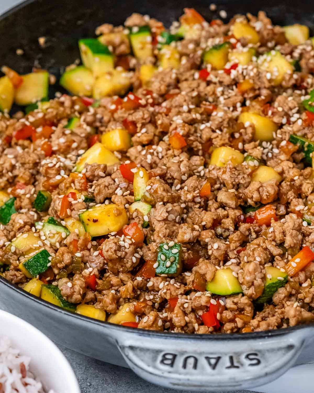 Ground turkey and vegetables in a skillet on a gray background.