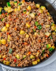 Ground turkey and vegetables in a skillet on a gray background.