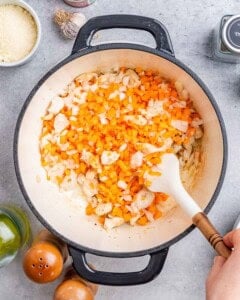 Stirring carrots and onions in a pot.