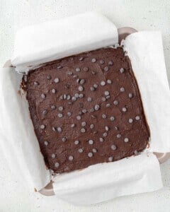 chocolate chips added over brownie batter in a pan.