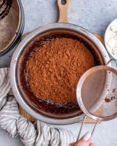 A sifter next to a large bowl with chocolate powder.