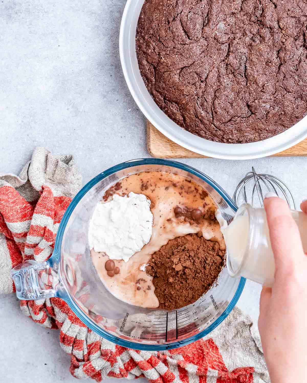 Pouring milk into dry ingredients in a large glass bowl.