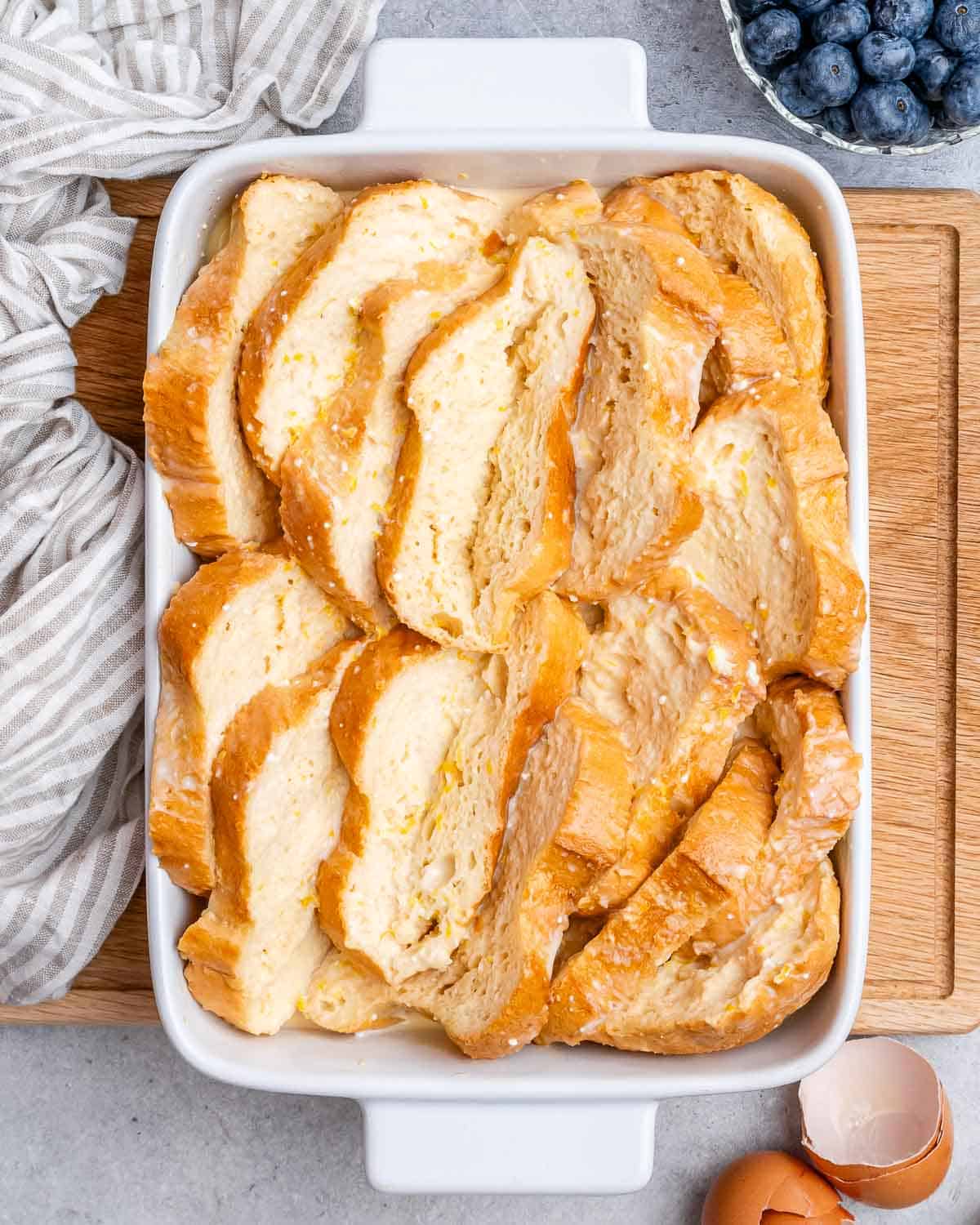 Sliced of egg soaked bread in a casserole dish.