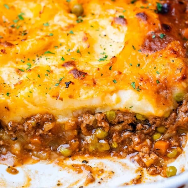 Shepherds pie in a white baking dish with meat showing at the bottom and potatoes on top.