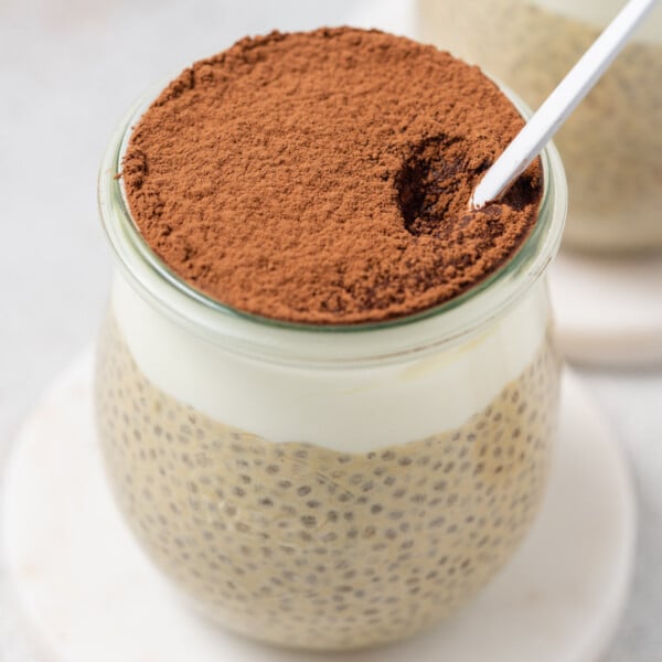 a jar with chia pudding and a layer of yogurt over the chia pudding, topped with cocoa powder.