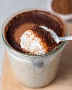 a jar with overnight oats topped with cocoa powder and a spoonful of the oats.