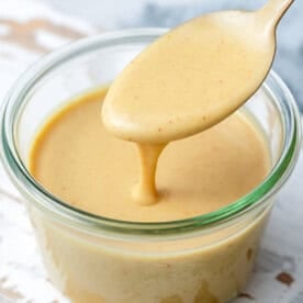 a jar with honey mustard dipping sauce with a spoonful in the jar.