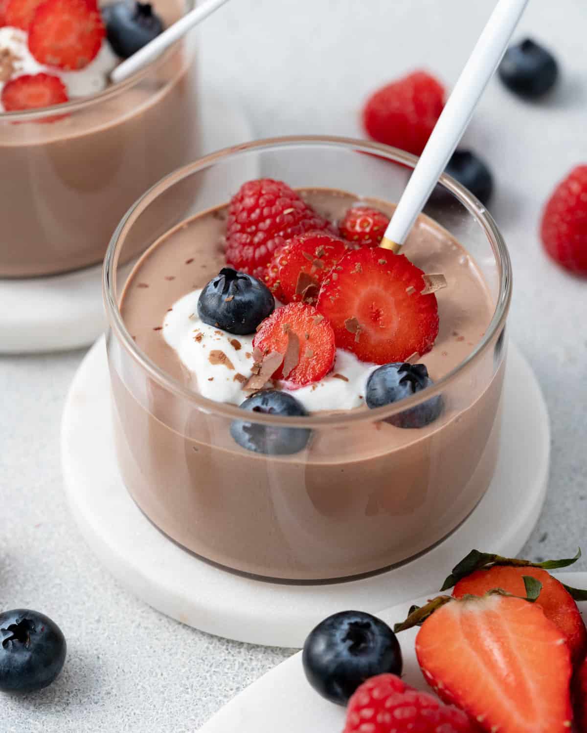 Close-up of mousse with fresh berries and whipped cottage cheese, with a few strawberries on the side.