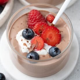 a glass jar filled with chocolate mousse, topped with a dollop of yogurt and fresh berries.