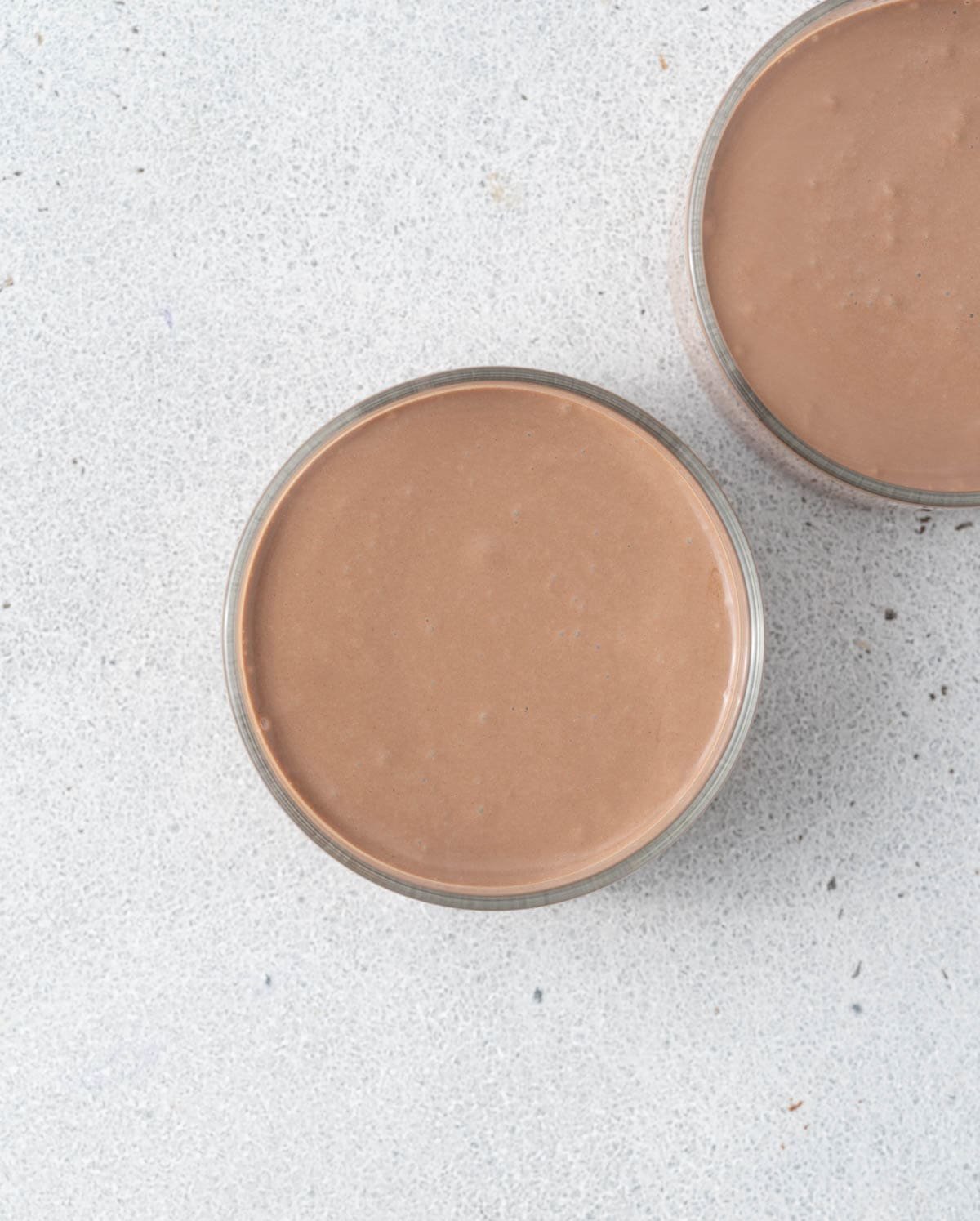 Two mousse-filled cups without toppings, smooth and creamy chocolate layer visible.