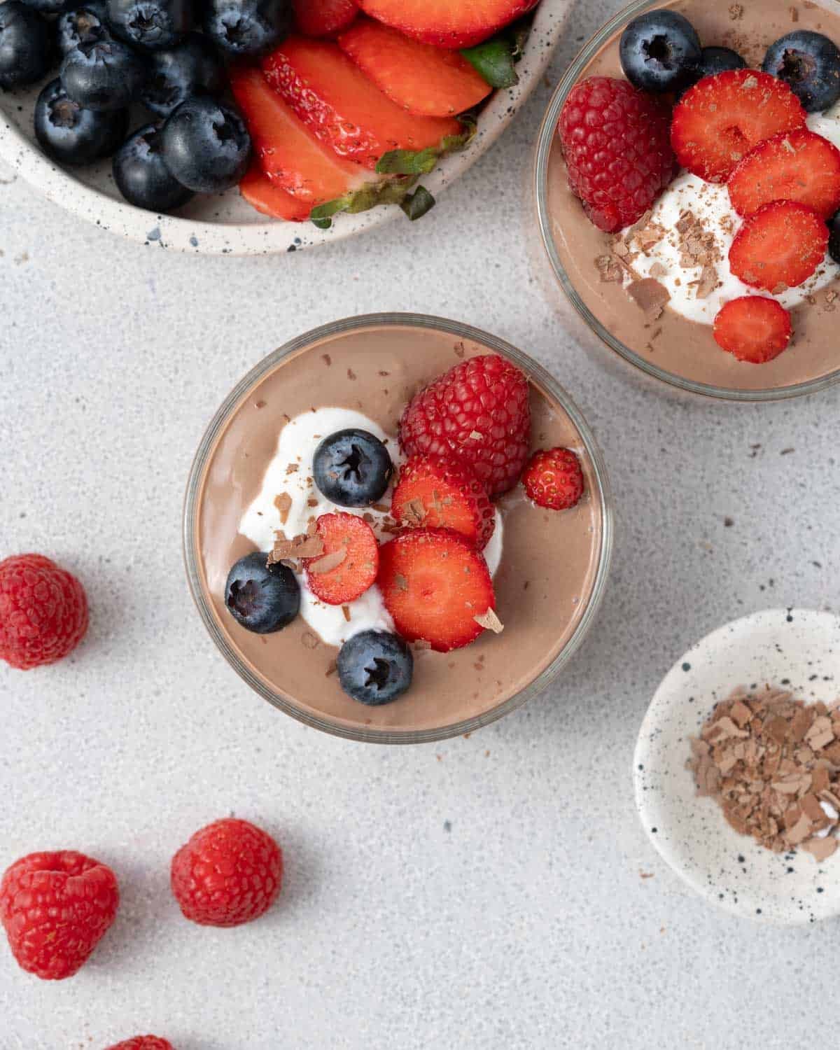 Overhead of mousse with fruit and whipped topping, framed by scattered berries.