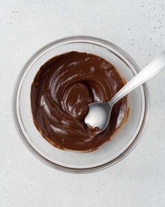 A bowl of melted dark chocolate with a spoon.