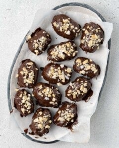 Overhead shot of the full platter of finished date Snickers with a sprinkle of chopped nuts on top.