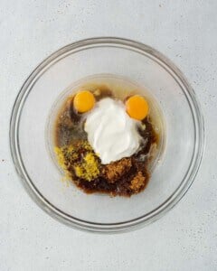egg, yogurt, sugar, and oil, added to a bowl.
