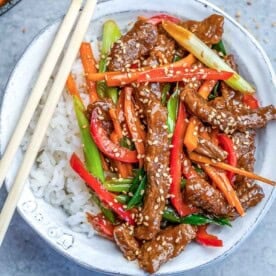 a round bowl filled with rice topped with mongolian beef stir fry.