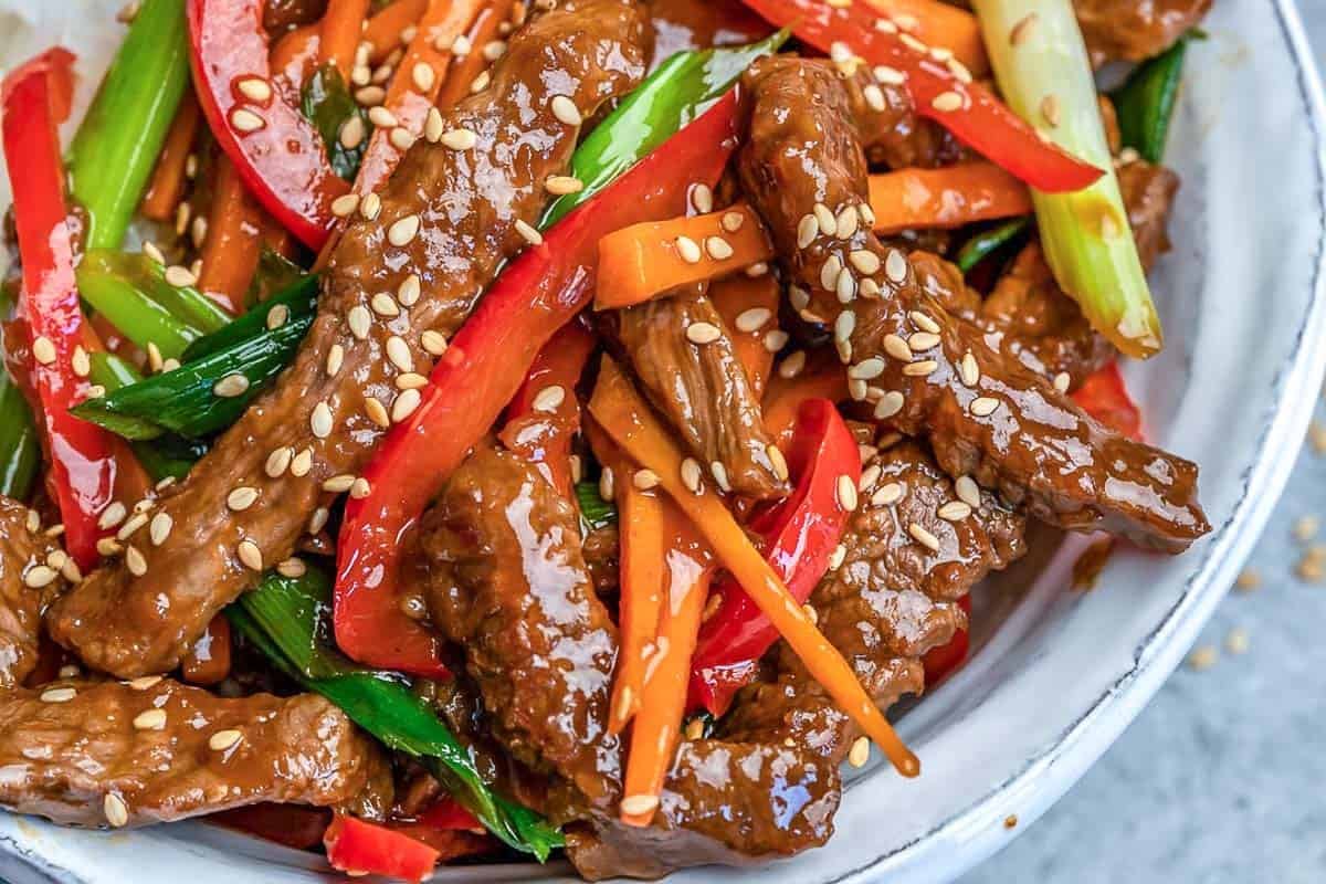 beef stir fry served with bell peppers over a bowl of rice.