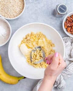 banana being mashed with a masher in a bowl.