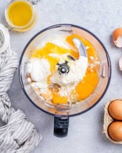 Food processor with cottage cheese cheesecake filling ingredients in it before blending.