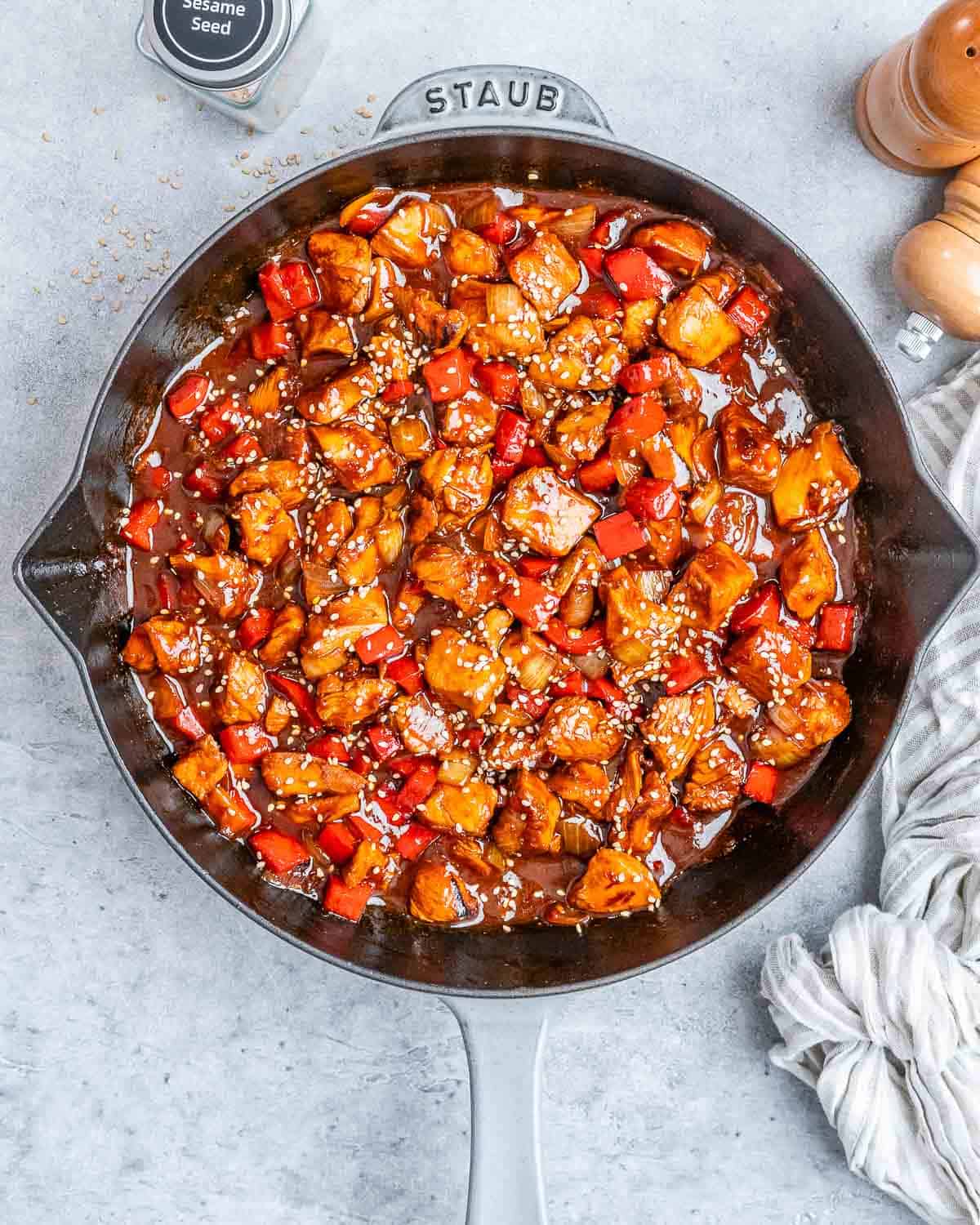 A skillet with cooked chicken bites in a red sauce.