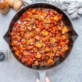 A skillet with cooked chicken bites in a red sauce.