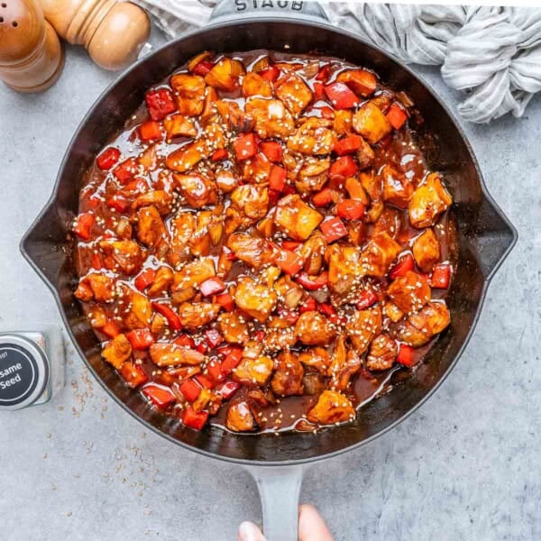 A skillet with cooked chicken bites in a red sauce.