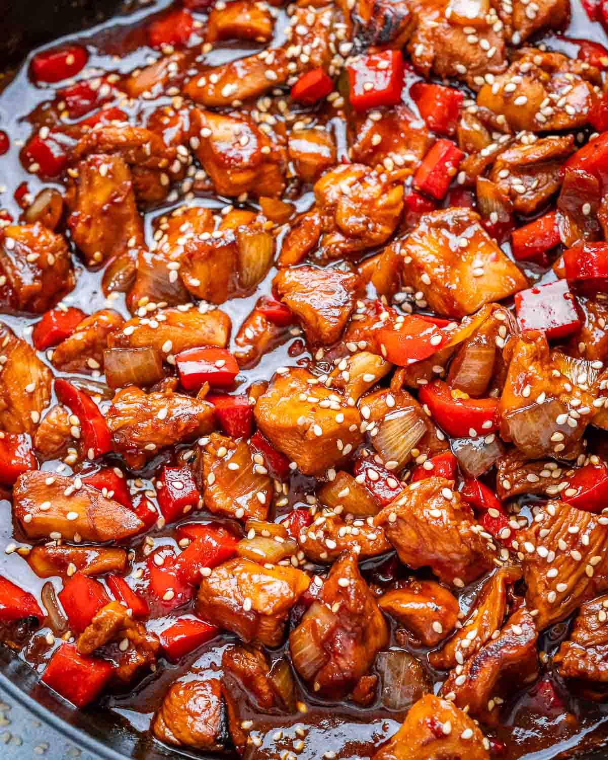 A skillet with cooked chicken bites in a red sauce.