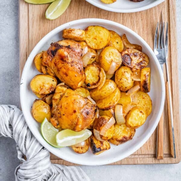 Overhead shot of a bowl filled with juicy chicken thighs and crispy roasted baby potatoes, ready to be served.