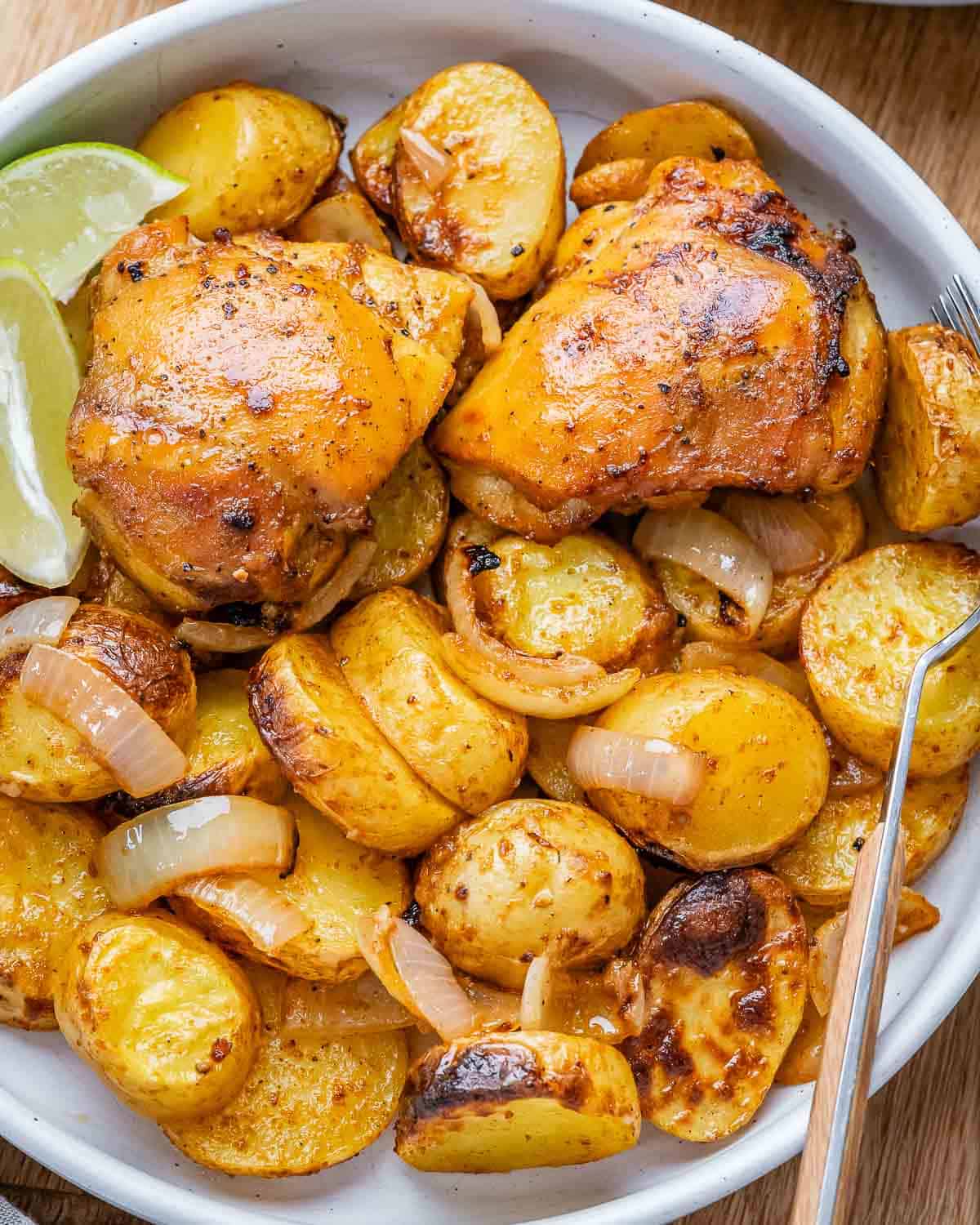 Zoomed-in look at roasted chicken thighs with caramelized edges and seasoned baby potatoes.