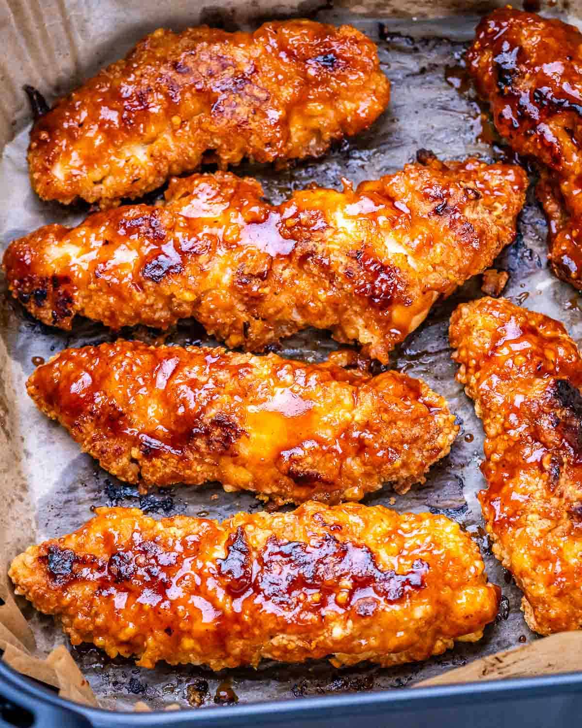 Crispy buffalo chicken tenders on parchment paper freshly cooked.