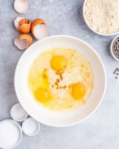 Mixing bowl with mashed bananas, eggs, vanilla, and coconut oil before being mixed.