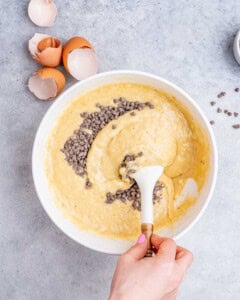 Mixing bowl showing banana bread batter with chocolate chips being stirred in.