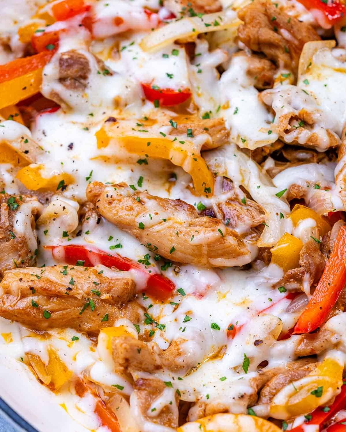 Close-up shot of cheesy Chicken Philly mixture with juicy chicken strips, bell peppers, and onions.