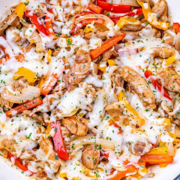Final dish close-up of a skillet full of cheesy Chicken Philly Cheesesteak, garnished with herbs.
