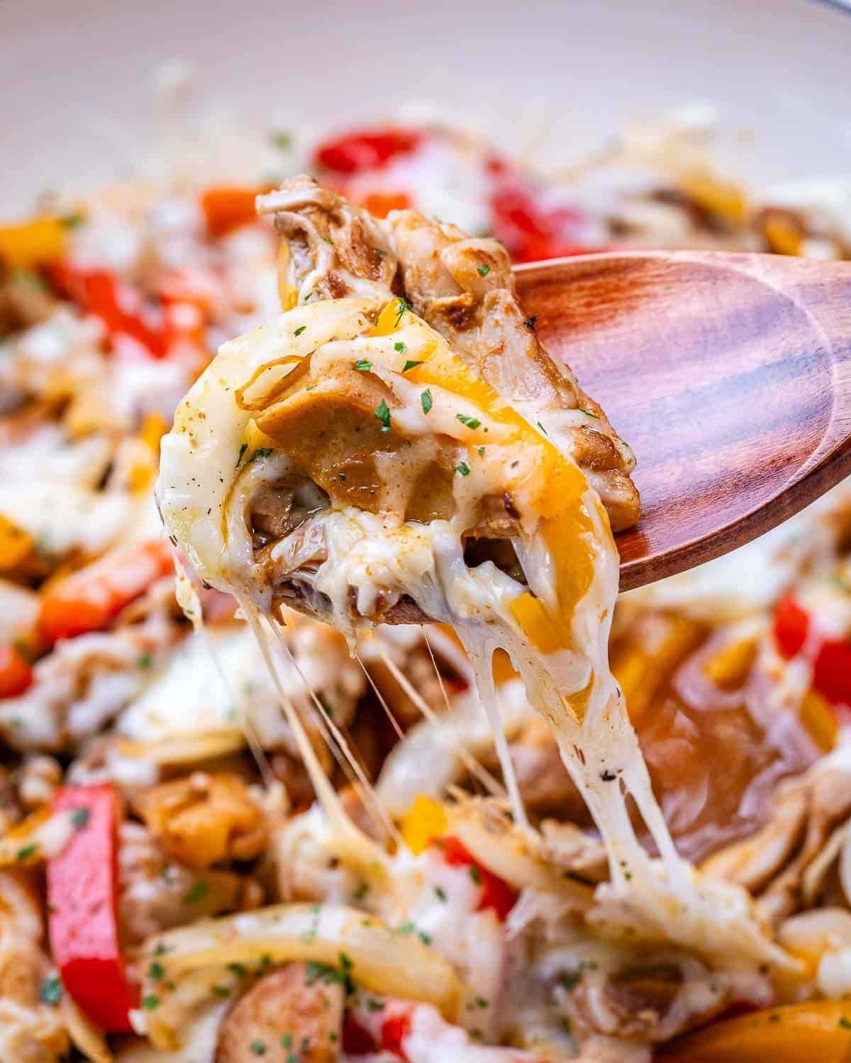 Spoonful of hot Chicken Philly mixture lifted from skillet with gooey melted cheese and tender chicken.