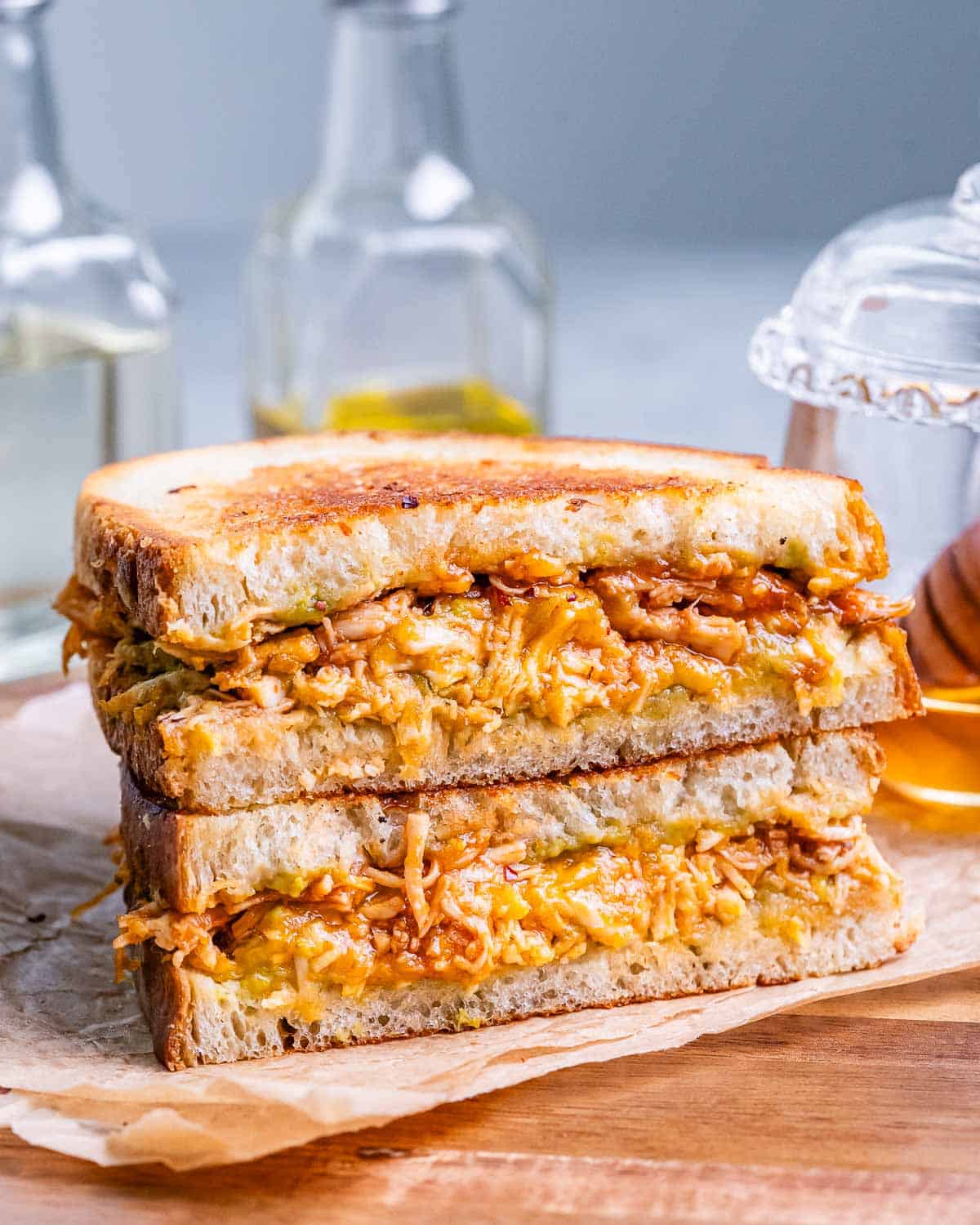 A toasted chipotle chicken avocado melt sandwich cut in half and laying on top of each other.