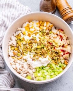 Chopped ingredients on top of chicken in a white bowl.