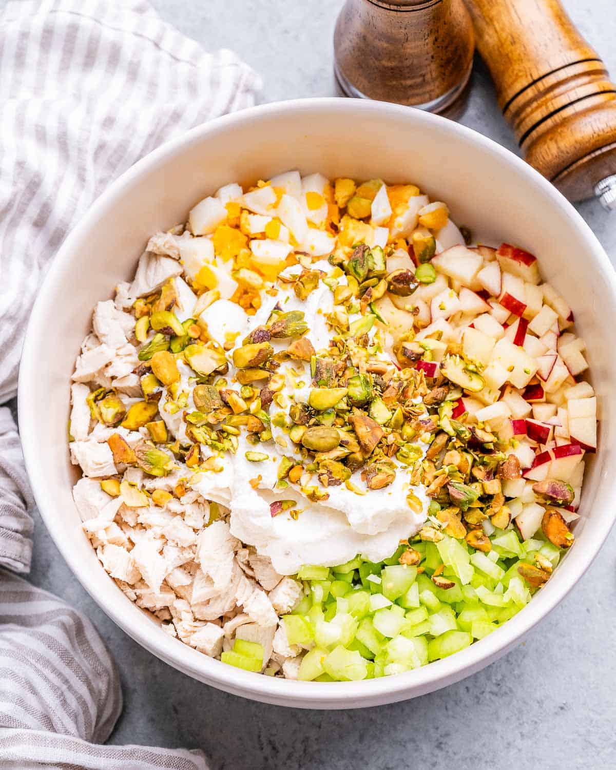 Chopped ingredients on top of chicken in a white bowl.
