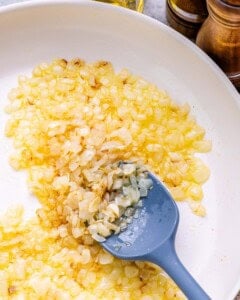sauteeing onions and garlic in a white pan