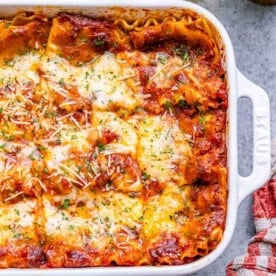 a white dish with lasagna topped with melted cheese.