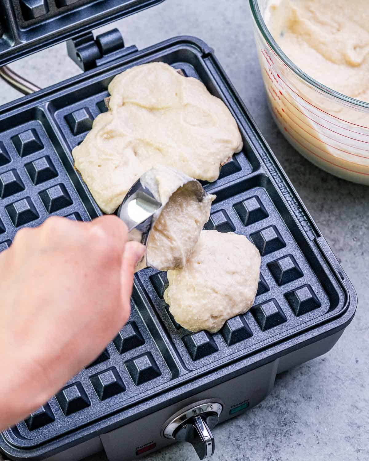 batter being poured onto the waffle maker. 