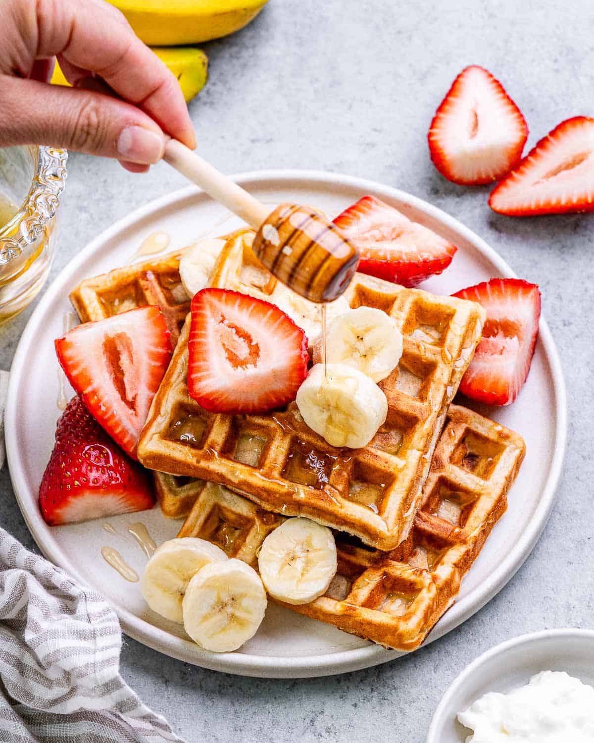 honey being added over waffles on a plate.
