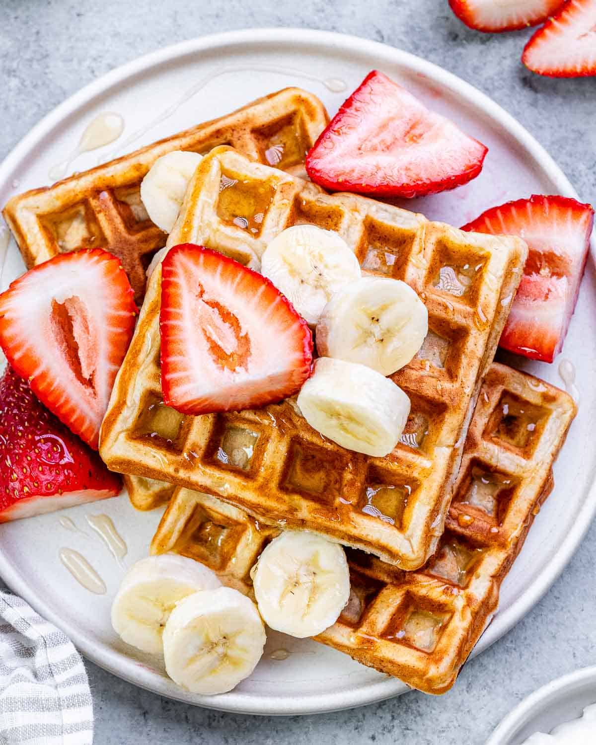 a round white plate with waffles on top of it. 