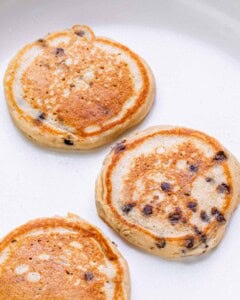 Three golden brown pancakes cooling on a white background