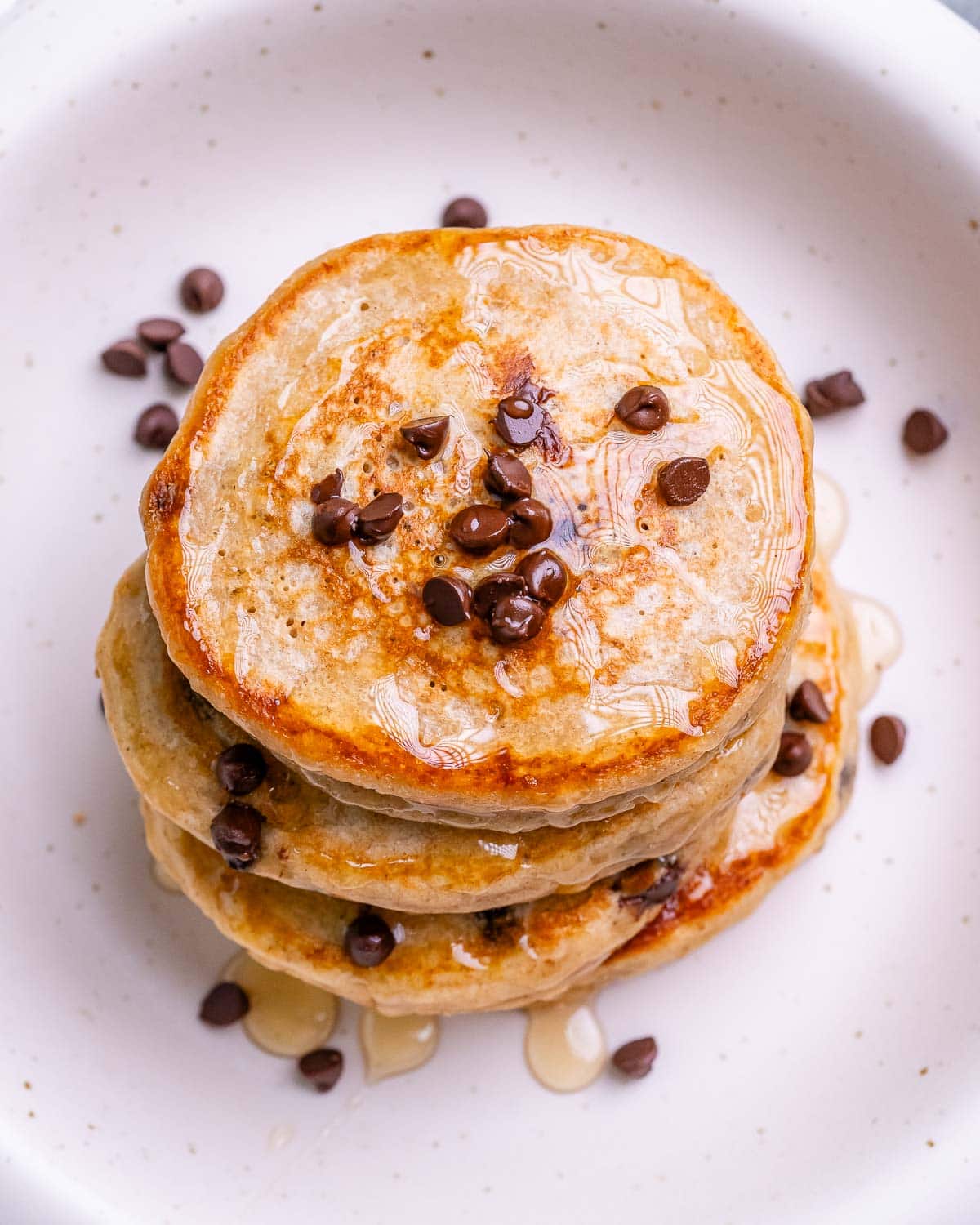 Overhead view of a pancake stack topped with melted chocolate chips and honey drizzle.