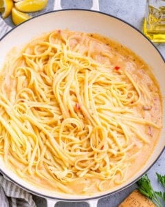 Cooked linguine added to the creamy sauce in the skillet.