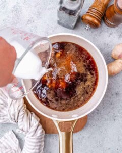 Pouring liquid into a cup with teriyaki sauce.