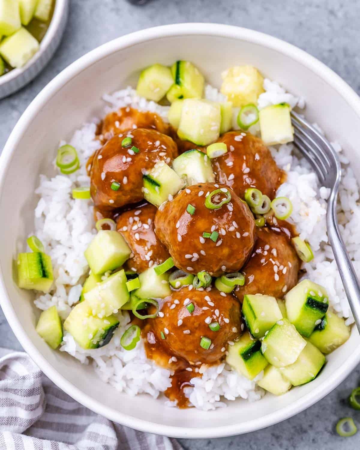 Meatballs over rice, topped with chopped cucumber.