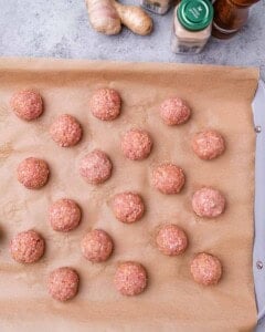 Raw meat balls on a baking tray.
