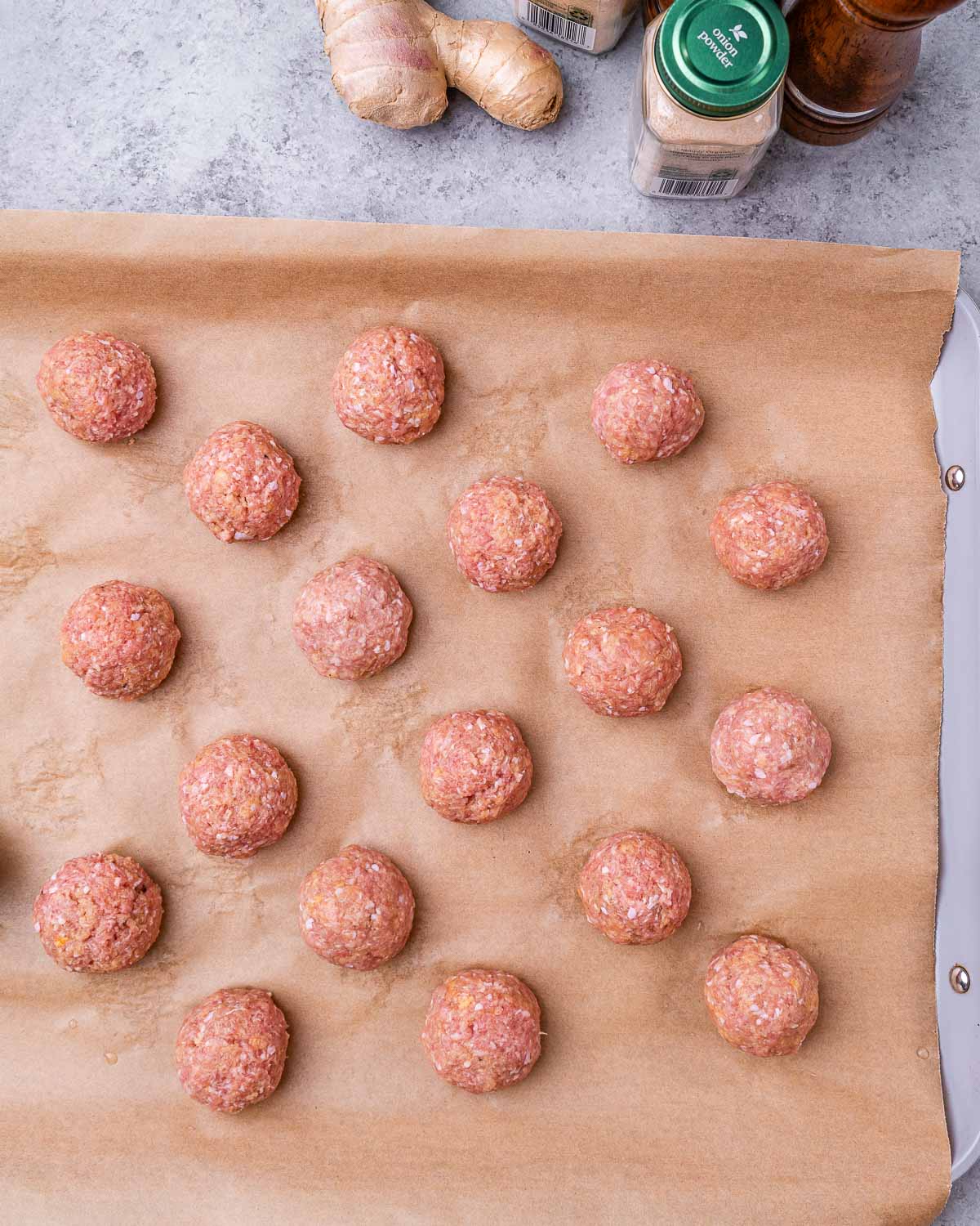 Raw meat balls on a baking tray.